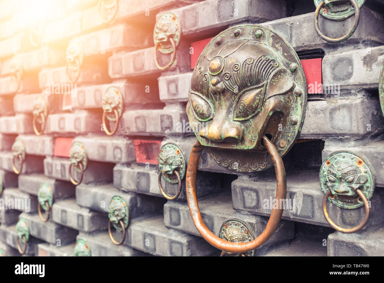 Ancient iron lions head door knocker situated on a brick wall . China . Stock Photo