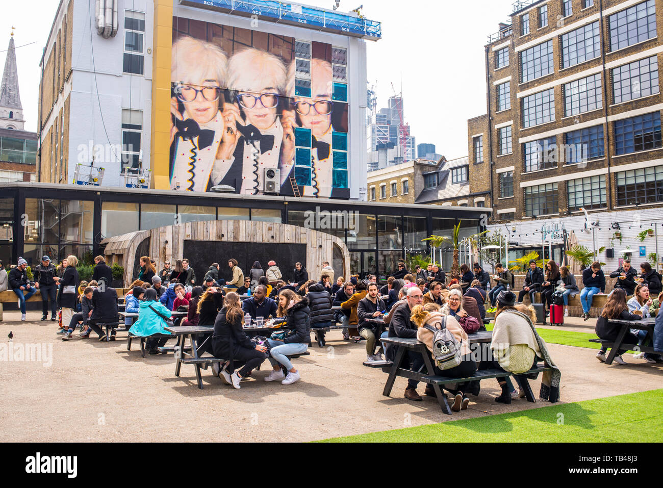 Pop up Outdoor food area with people eating outiside and mural street art celebrating Andy Warhol at The Old Truman Brewery, Ely's Yard, Shoreditch Stock Photo
