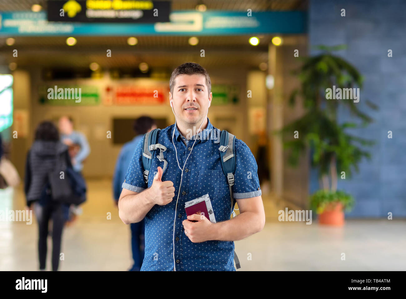 Smiling tourist at airport departure terminal holding passport and boarding pass Stock Photo