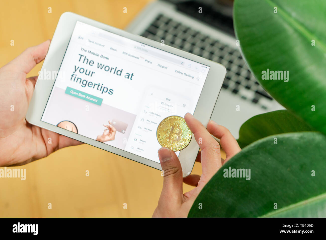 Ljubljana, Slovenia 29.4.2019: Businessman holding computer tablet with opened n26 bank's website and Bitcoin coin on a office desk Stock Photo