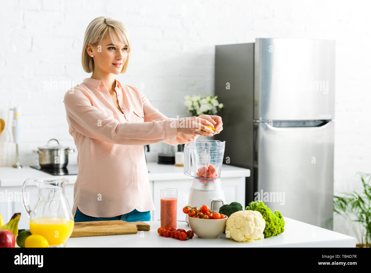 blonde pregnant young woman preparing food in kitchen Stock Photo