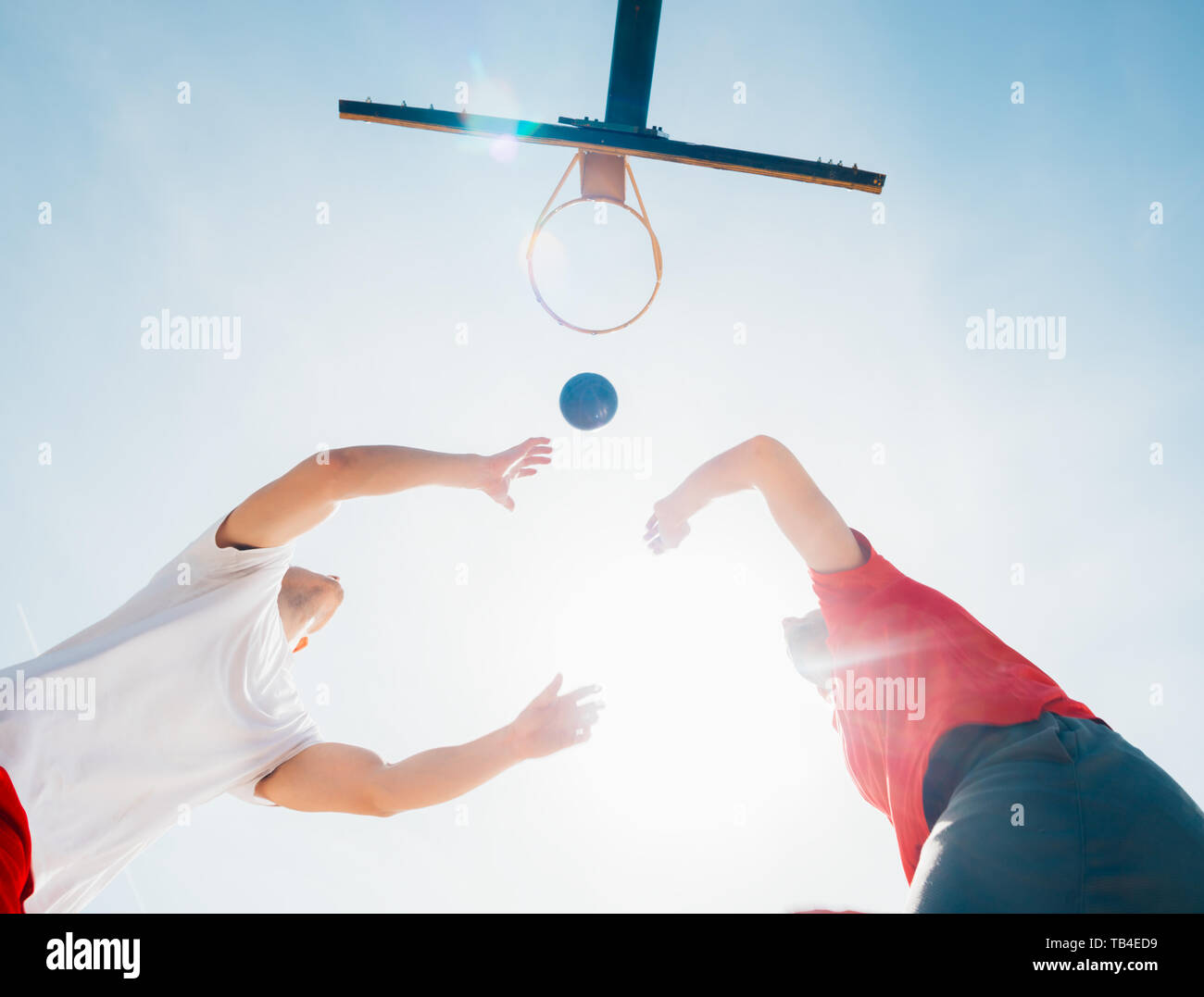 Two strong male basketball players play ball out doors fighting for a