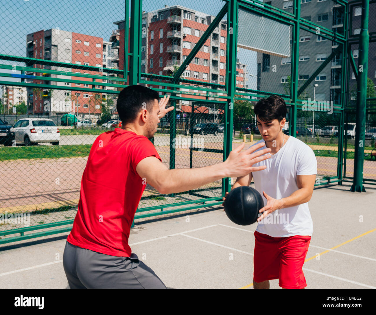 Two strong male basketball players play ball out doors fighting for a