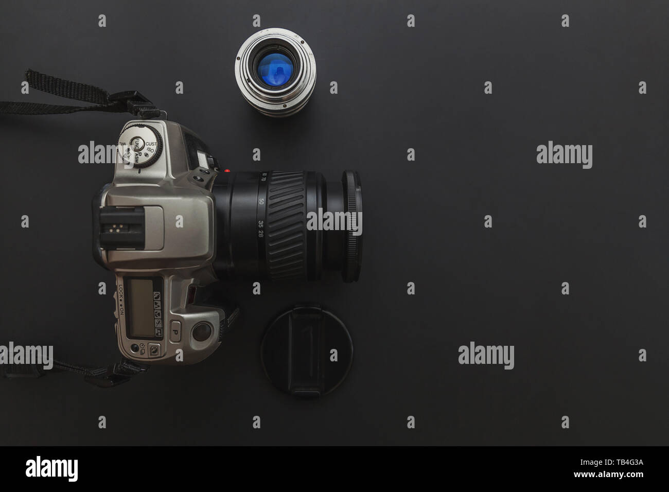 Photographer workplace with dslr camera system and lens on dark black ...