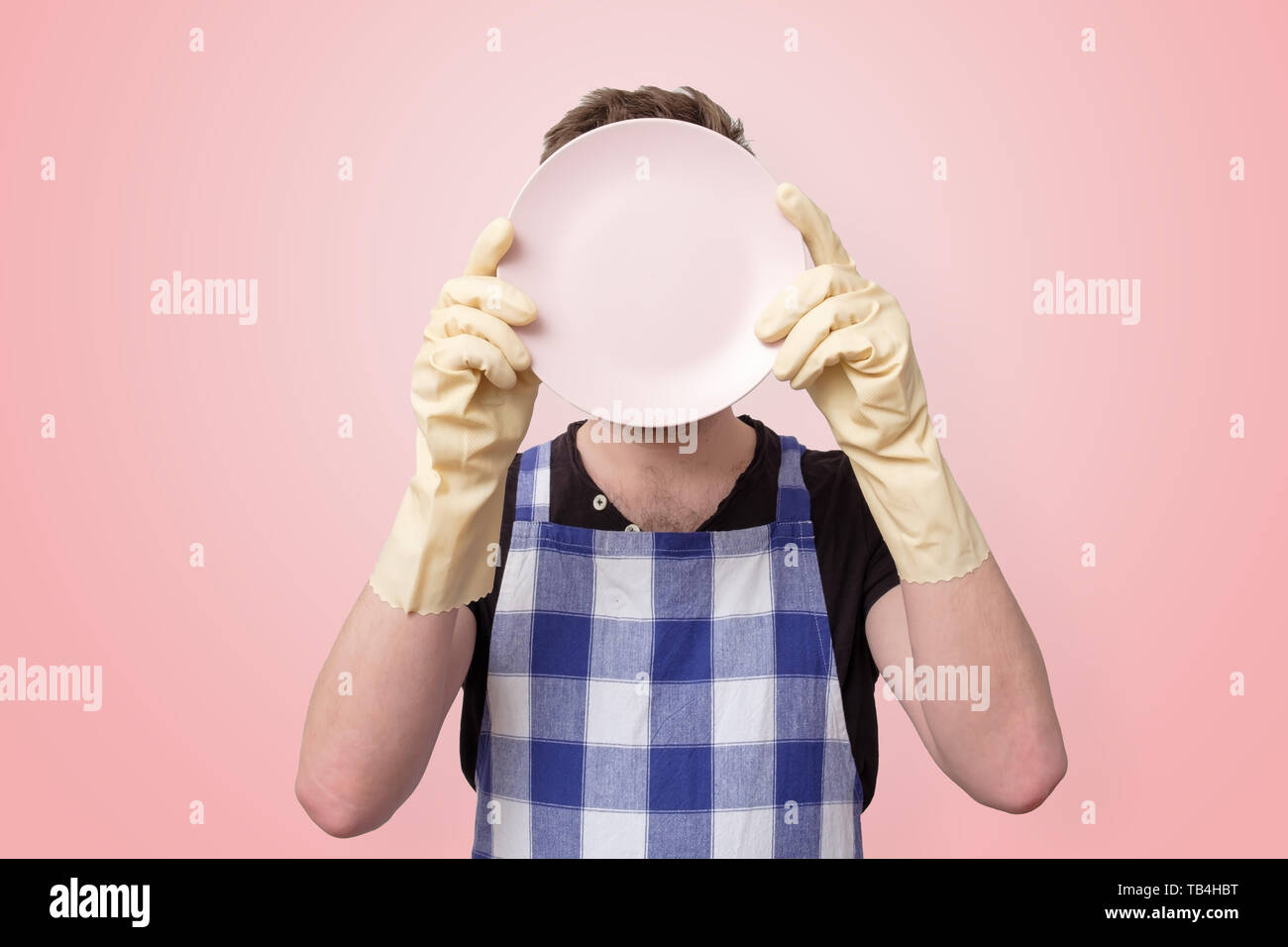 man in apron and rubber gloves holding clean plate Stock Photo