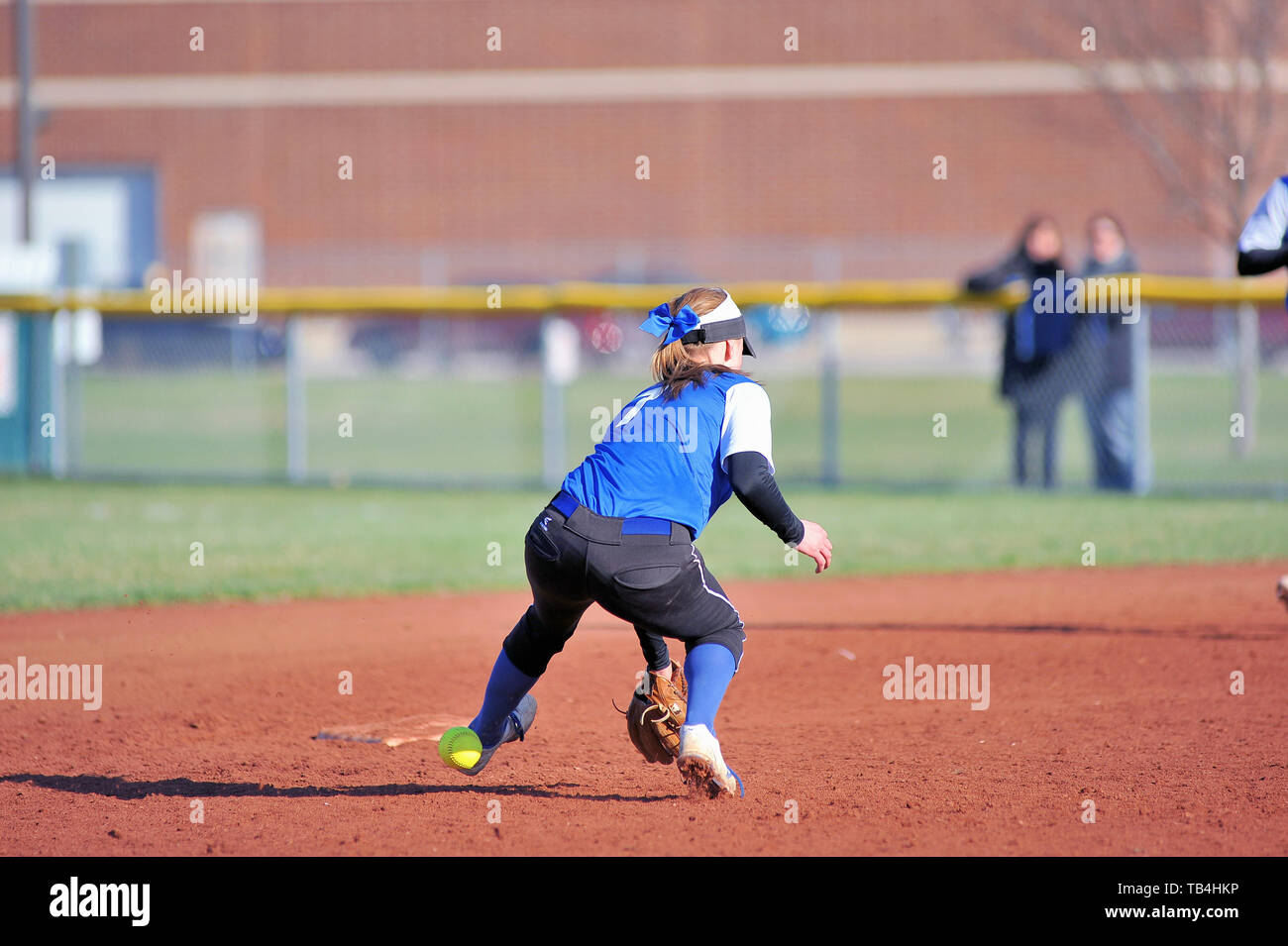 Shortstop unable to successfully field a ground ball that went through her legs for an error. USA. Stock Photo