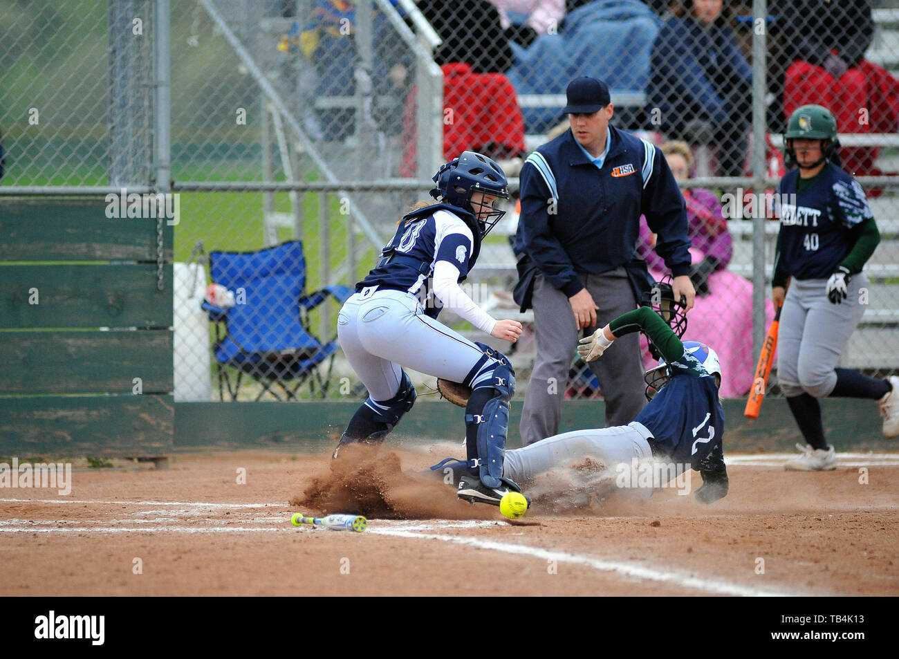 Runner slides in safely to the plate as throw from home was wild and eluded the catcher. USA. Stock Photo