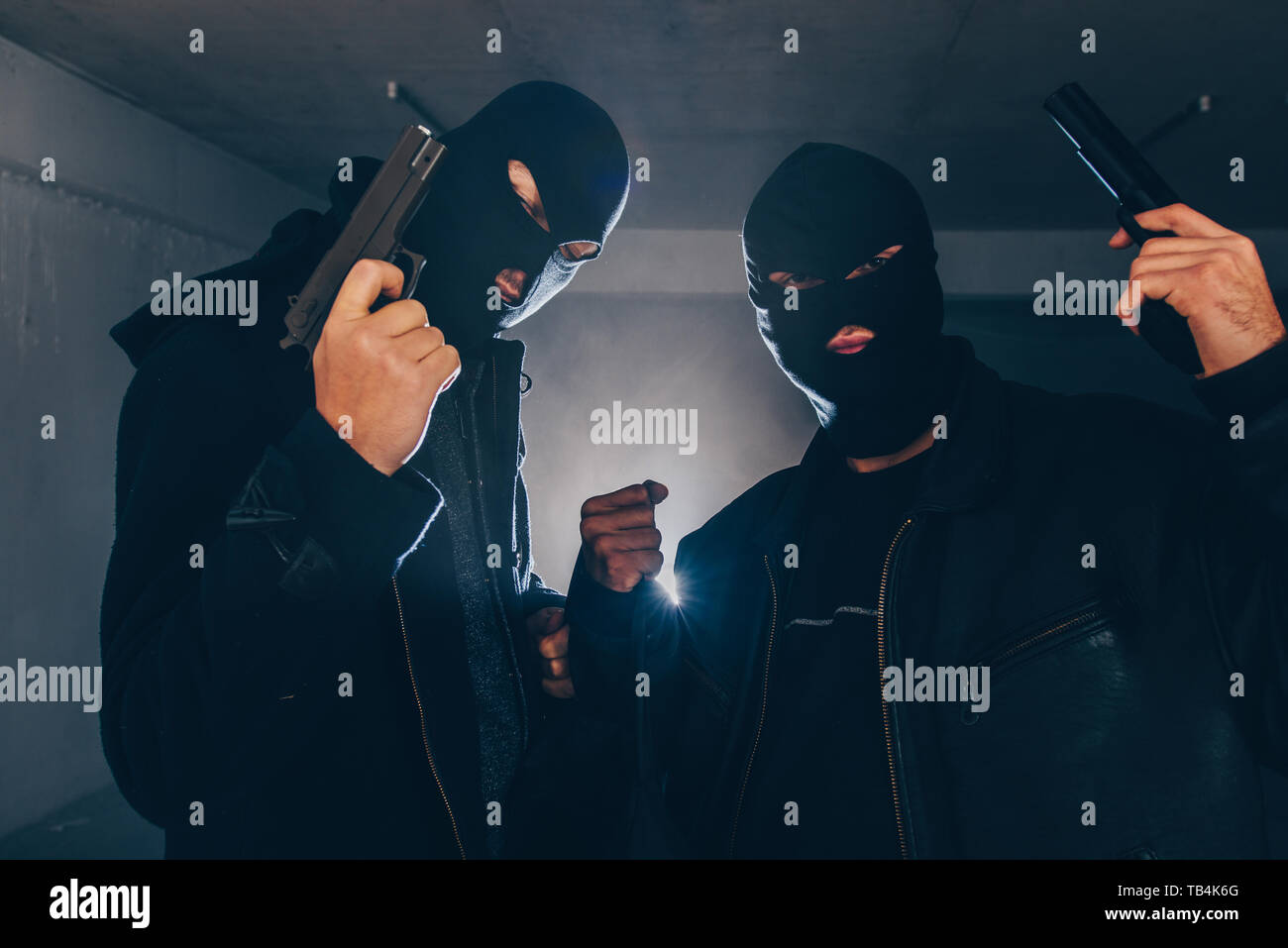 Masked men are holding guns in basement Stock Photo
