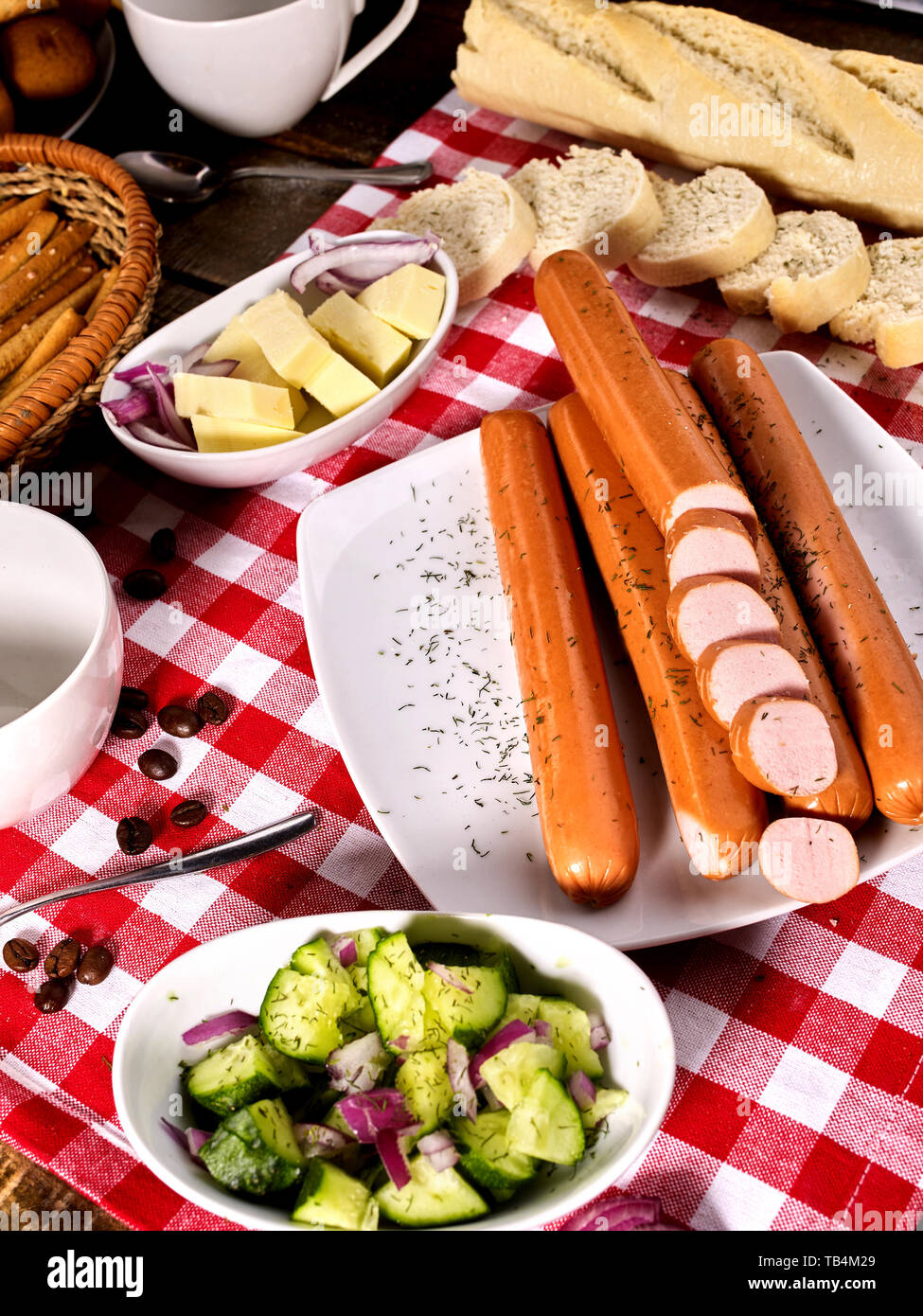 Sausage portion with baguette on table setting on checkered cloth Stock Photo