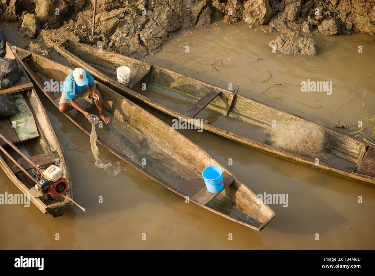 Man bailing water from his wooden boat docked on the riverbank of the Ucayali River, Peruvian Amazon Basin, Loreto Department, Peru Stock Photo