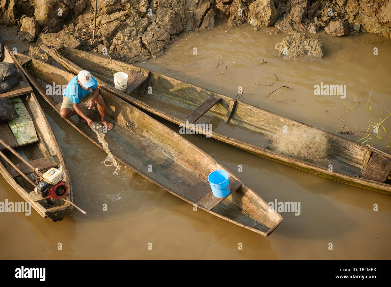 Man bailing water from his wooden boat docked on the riverbank of the Ucayali River, Peruvian Amazon Basin, Loreto Department, Peru Stock Photo
