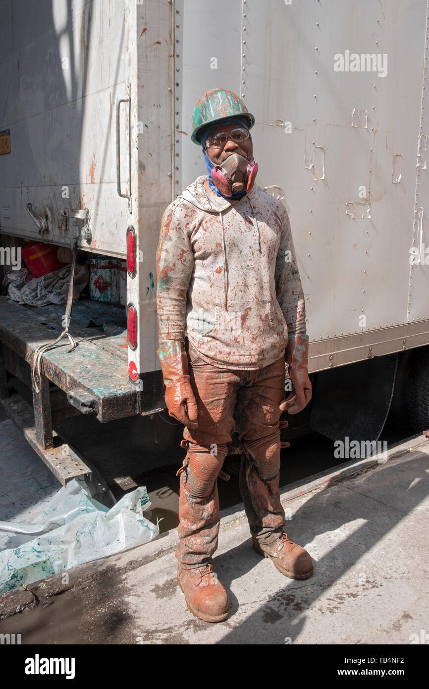 Posed portrait of a construction worker covered in paint on a subway renovation project on