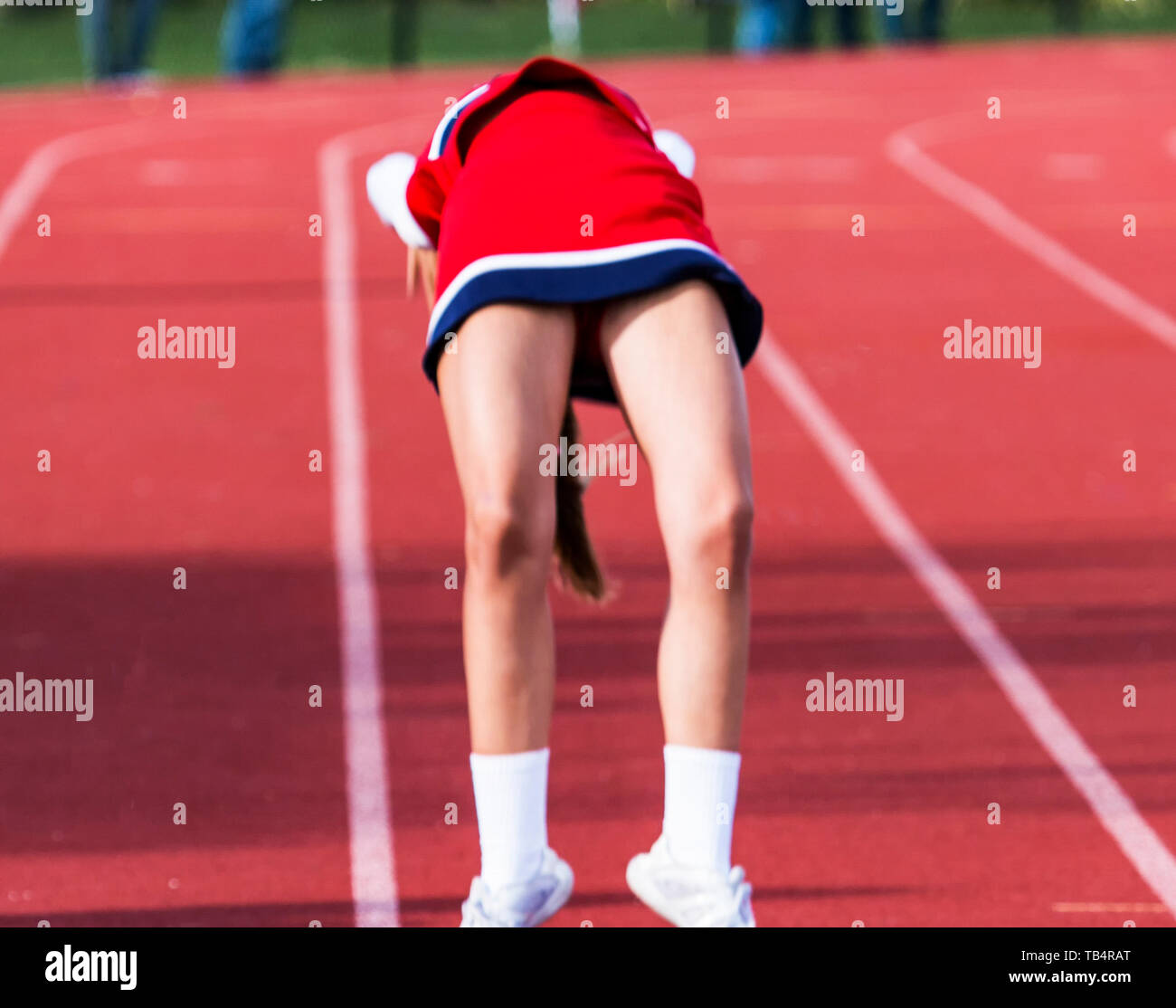 A high school cheerleader performing a back flip on the track for the fans at a football game. Stock Photo