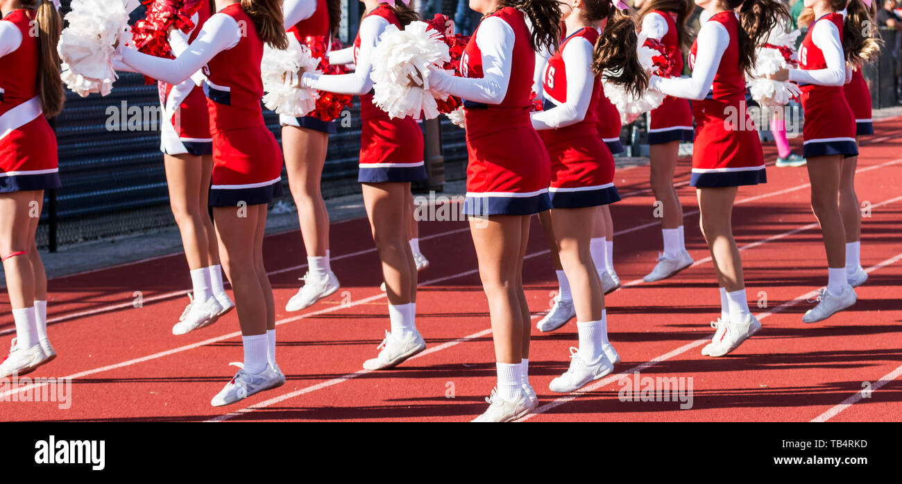 A group of high school cheerleaders are motivating the fans by cheering during a football game. Stock Photo