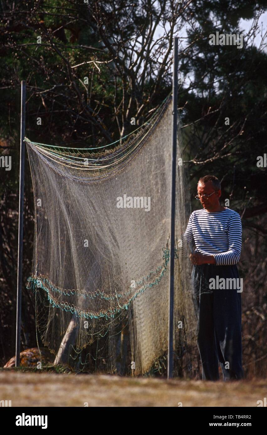 A Man Cleaning Fishing Nets Stock Photo