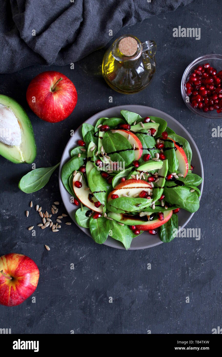 Fresh avocado salad with spinach, apple, pomegranate and sunflower seed on dark background. Top view with copy space. Stock Photo