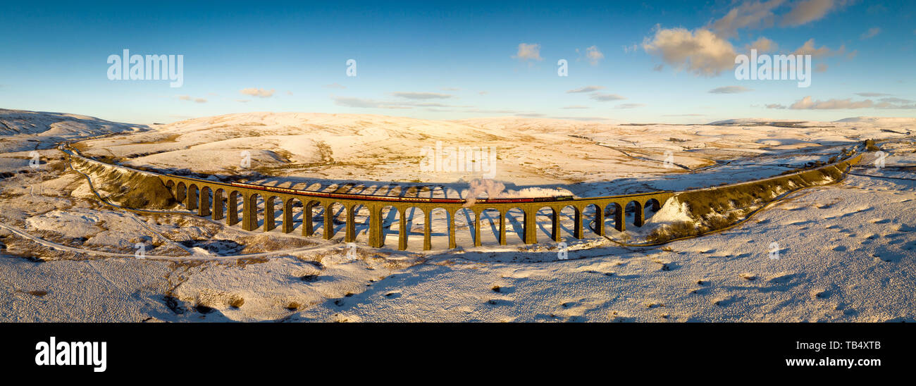 Aerial panorama of the steam train passing over Ribblehead Viaduct on the Settle Carlise Railway, in Snowy Yorkshire Dales Scenery Stock Photo