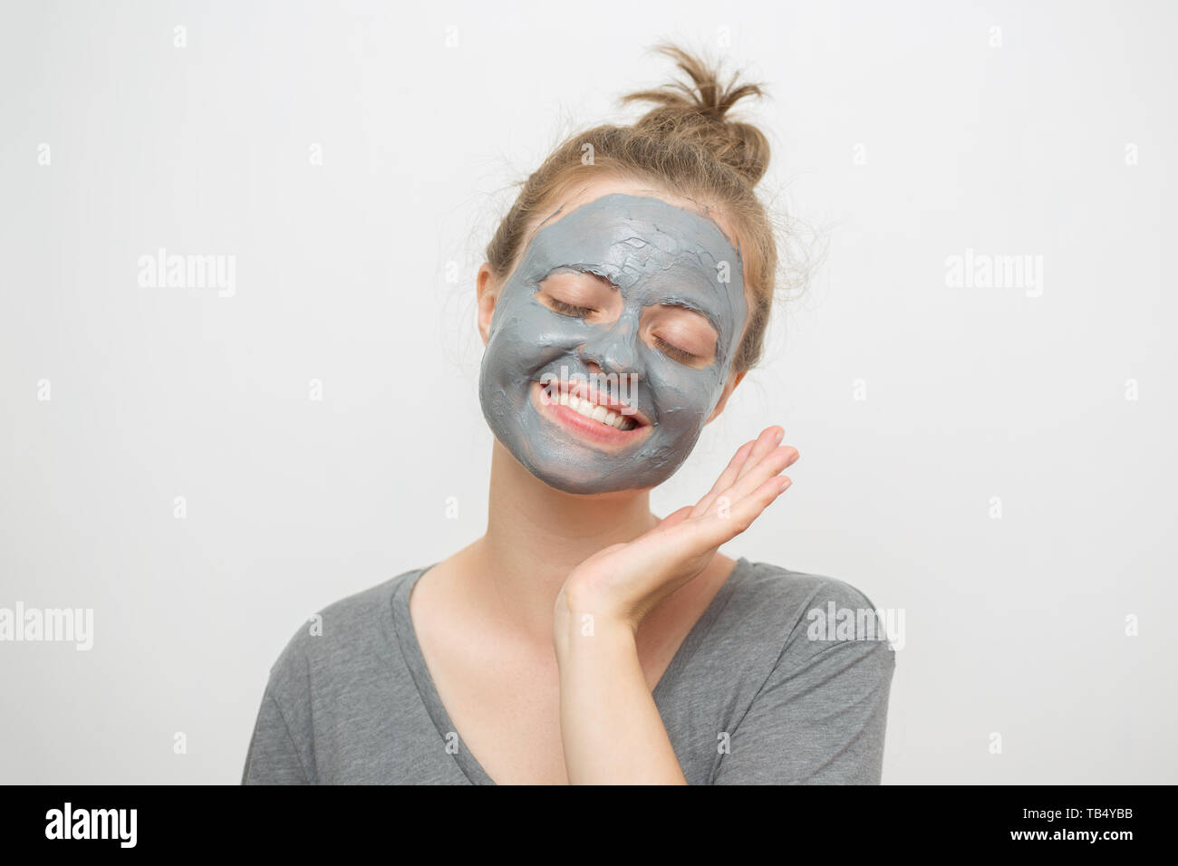 Young caucasian woman with black or grey facial clay mask on her face, smiling Stock Photo