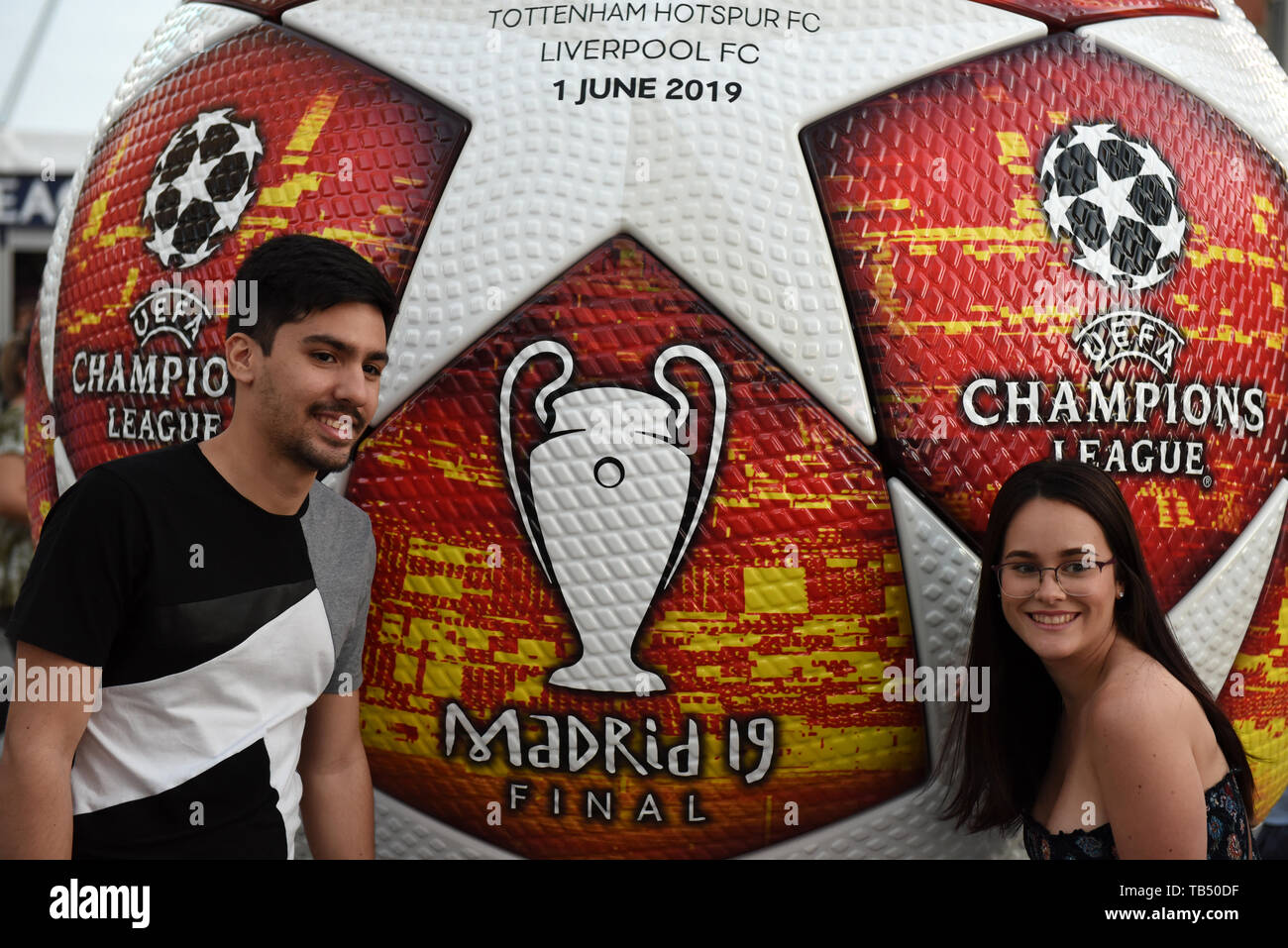 A couple are seen posing for a picture with an advertisement of the 2019 Champions League Final in Madrid. Madrid will host the UEFA Champions League final between Liverpool FC and Tottenham Hotspur on June 1, 2019 at the Wanda Metropolitano Stadium. Stock Photo