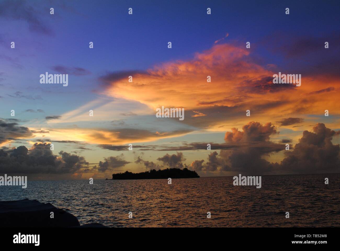 Beautiful clouds at sunset reflected in the waters of the Saipan lagoon, with the Managaha Island in the distance. Stock Photo
