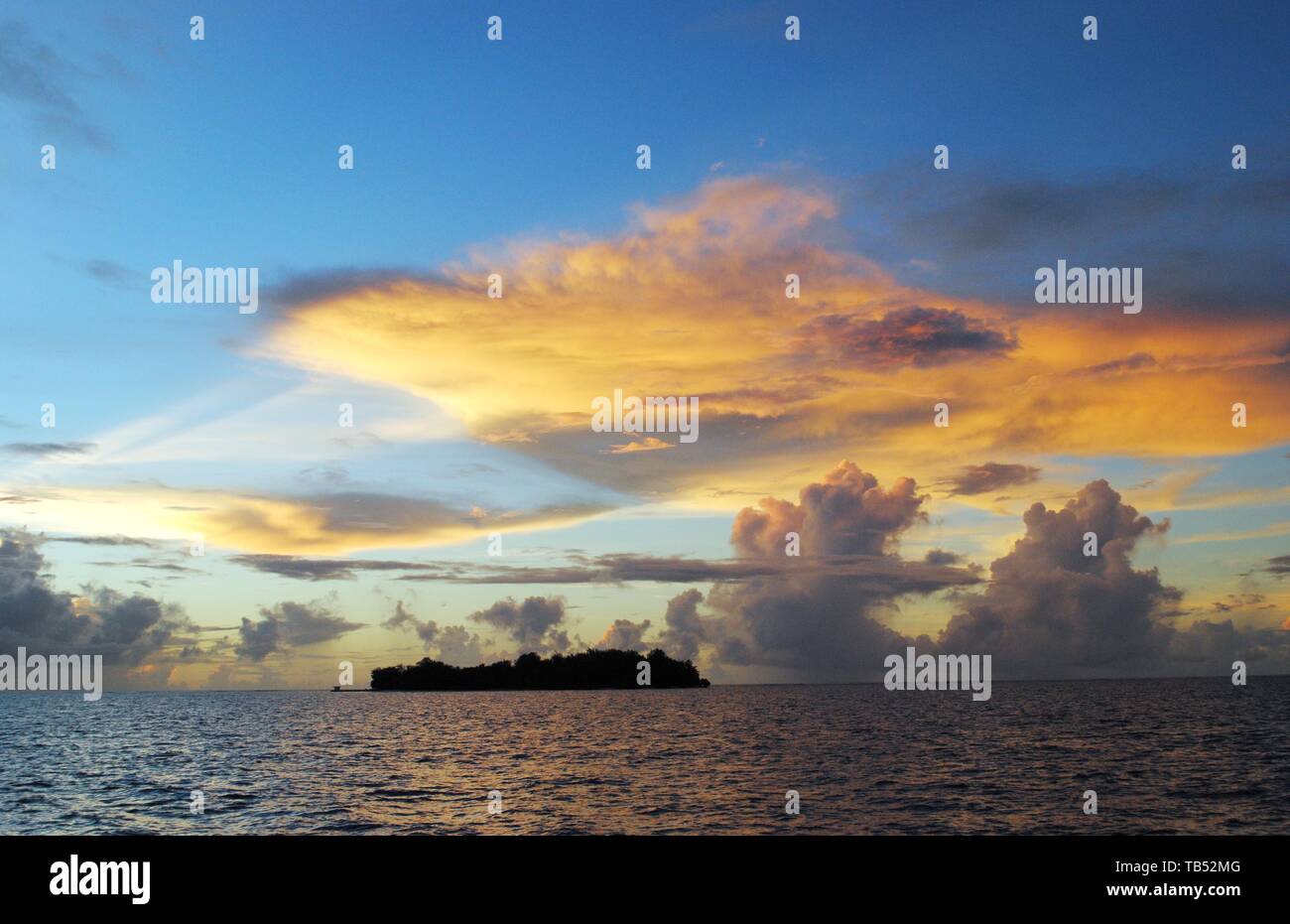 Magical play of clouds in the skies at sunset reflected in the waters of Saipan lagoon, with Managaha Island in view Stock Photo