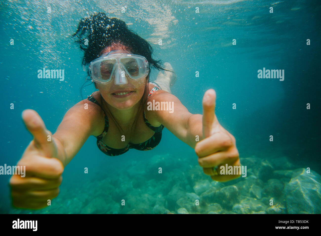 Woman diving in sea. Smiling female swimmer with diving mask gives