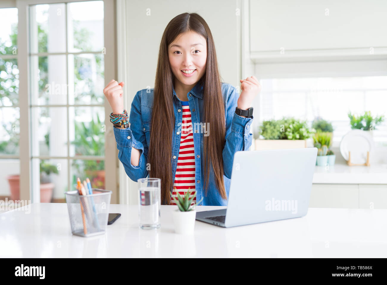 Beautiful Asian woman working using computer laptop celebrating ...