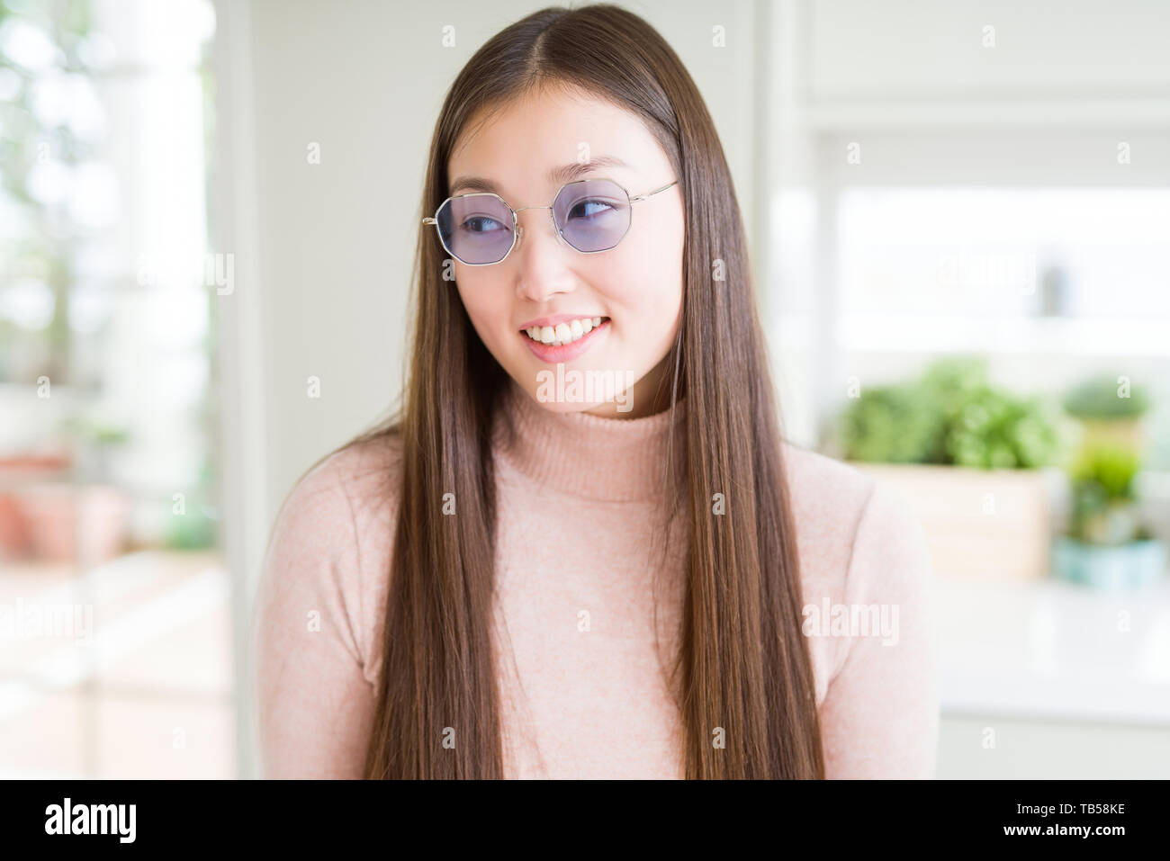 Beautiful Asian woman wearing glasses smiling looking side and staring ...
