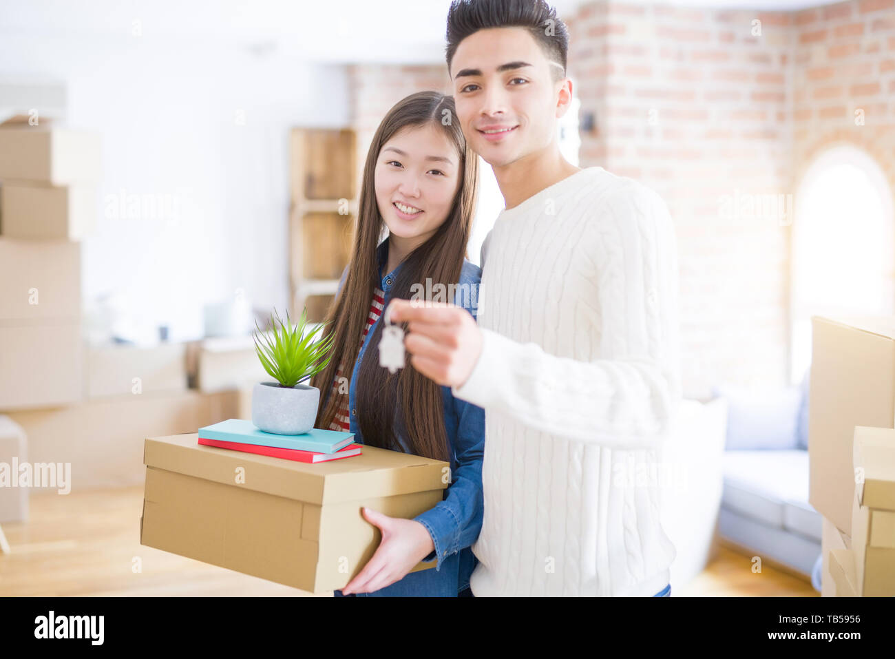 Young asian couple holding keys of new house, smiling happy and excited ...