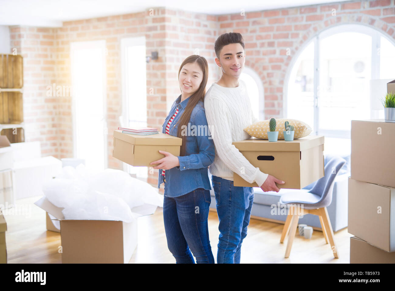 Beautiful young asian couple looking happy holding cardboard boxes ...