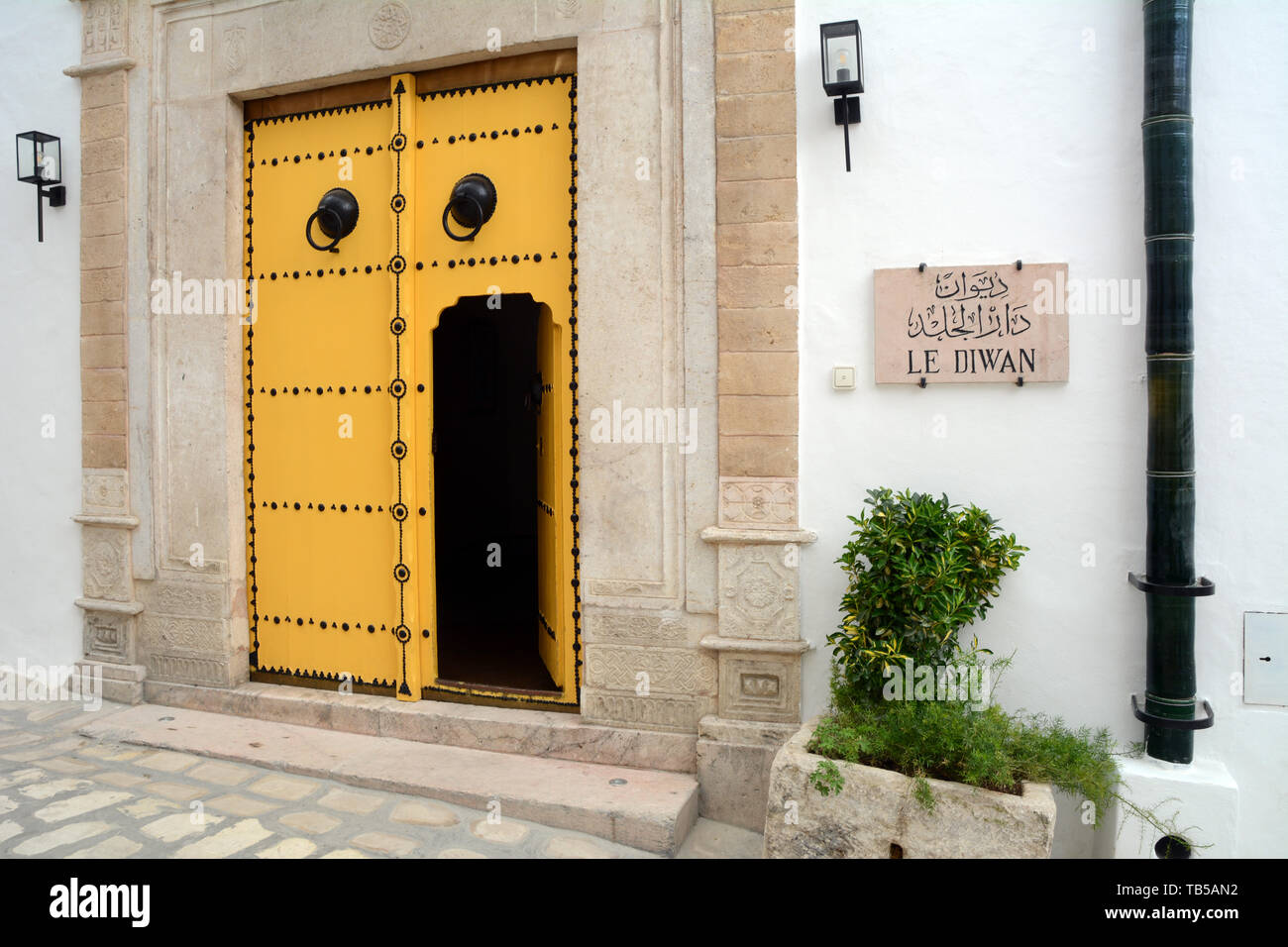 The traditional yellow door at an upscale restaurant in a16th century building in an alleyway of the medina (old city) of Tunis, Tunisia. Stock Photo