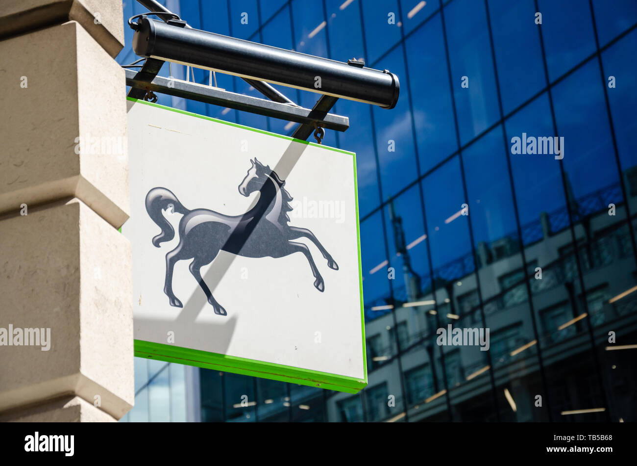 A Lloyds bank branch sign seen against a modern glass building on Leadenhall Street in London. Stock Photo