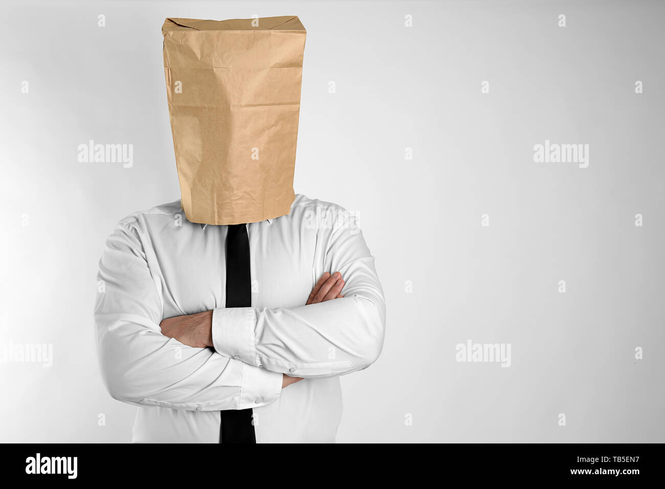 Businessman with paper bag on his head against light background Stock Photo