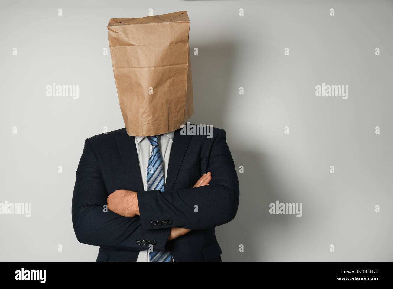 Businessman with paper bag on his head against light background Stock Photo