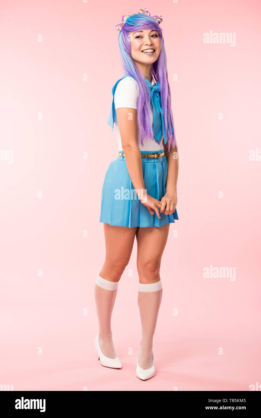 Full length view of otaku girl in purple wig smiling on pink Stock Photo
