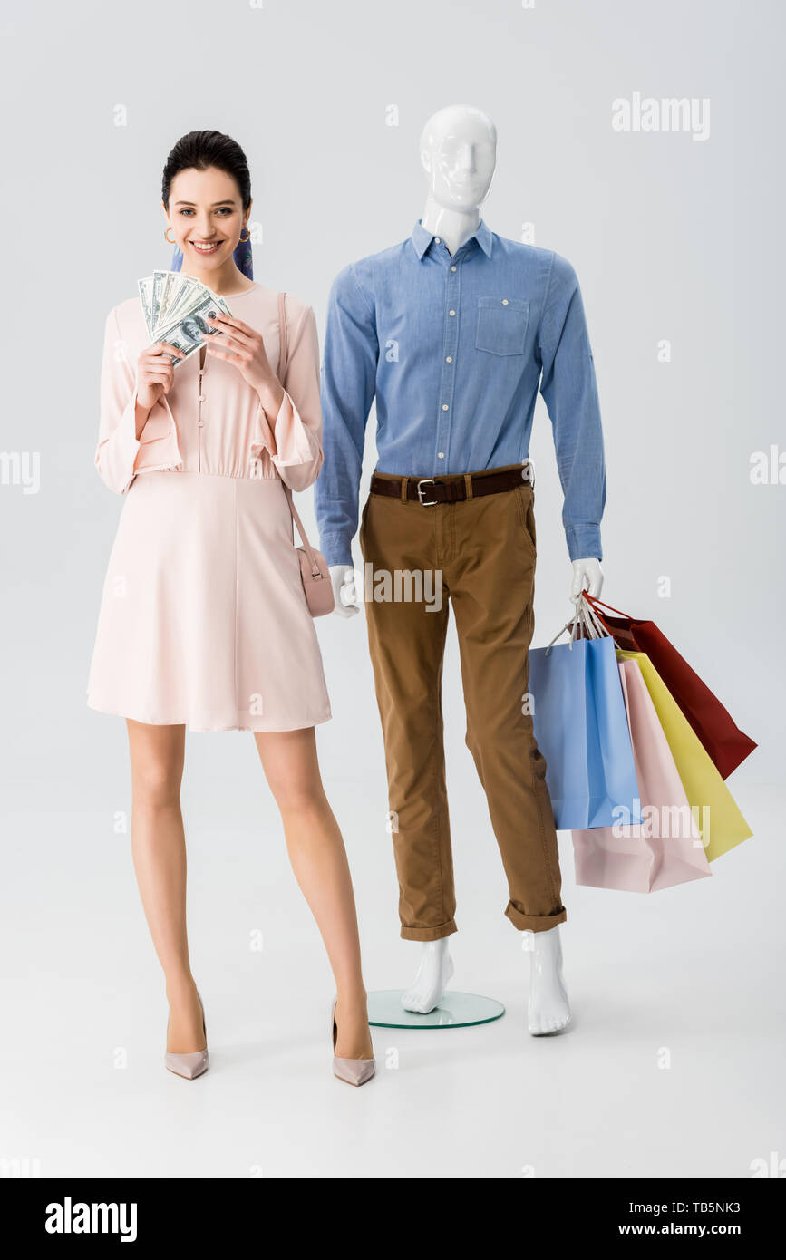 beautiful girl holding money while mannequin holding shopping bags on