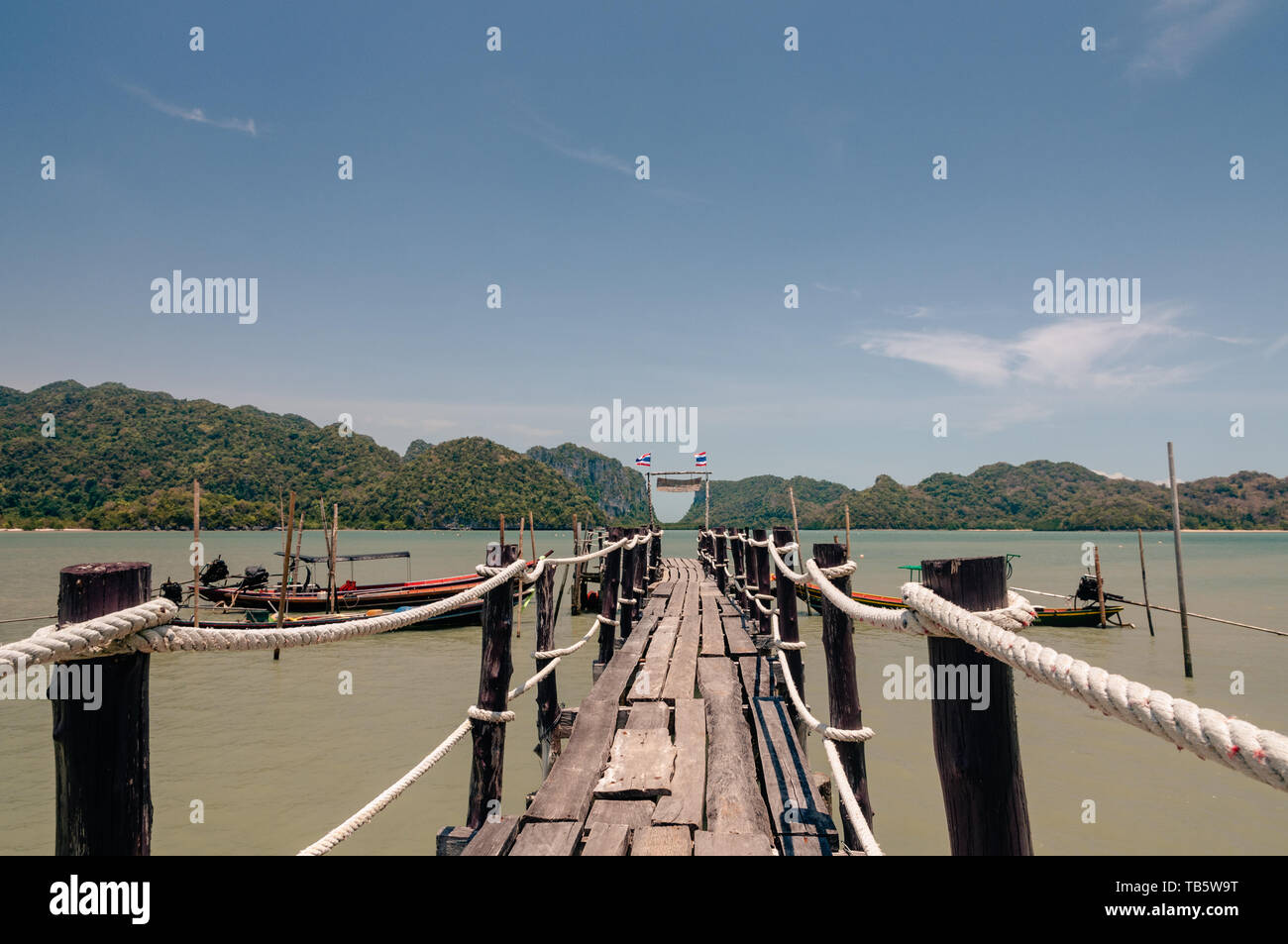 Wooden pier and thai long tail boats in Talet bay at Nakhon Si Thammarat province of Thailand. Stock Photo