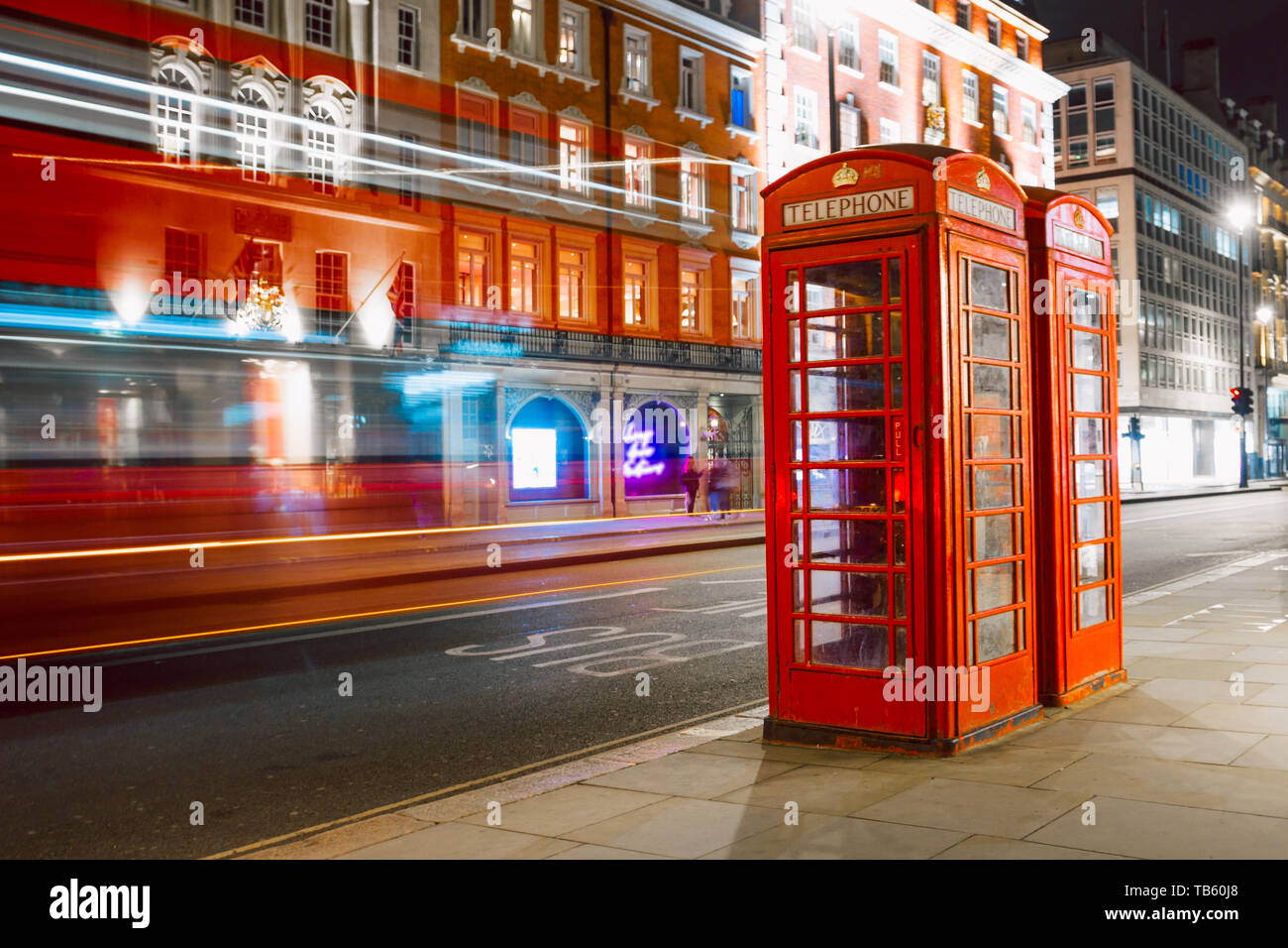 Light trails of a double decker bus next to the iconic telephone booth in London Stock Photo