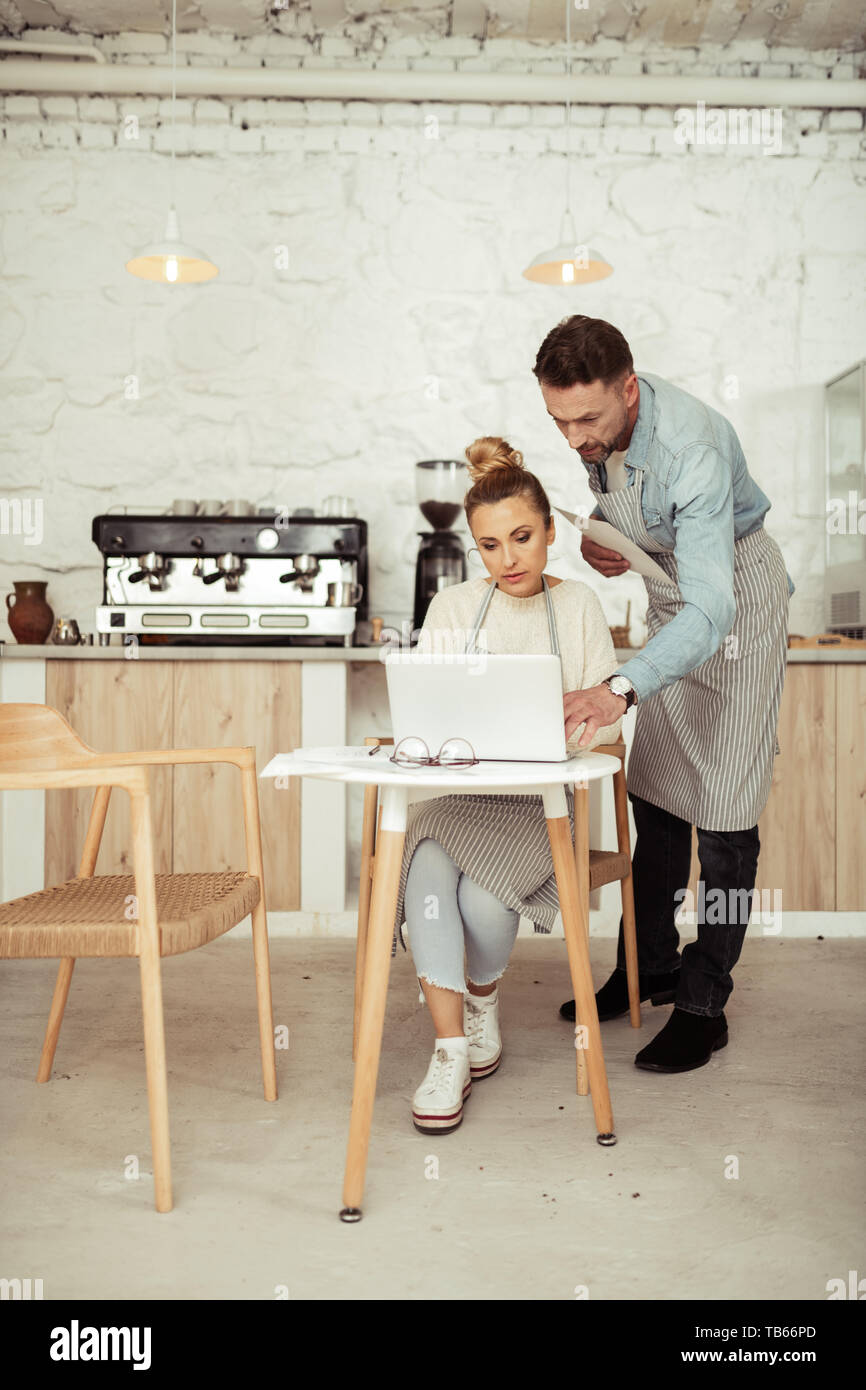 Helping hand. Concentrated man helping his partner sitting at the ...