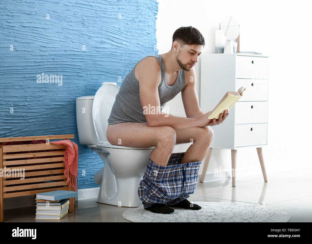 Man reading book while sitting on toilet bowl at home Stock Photo Alamy