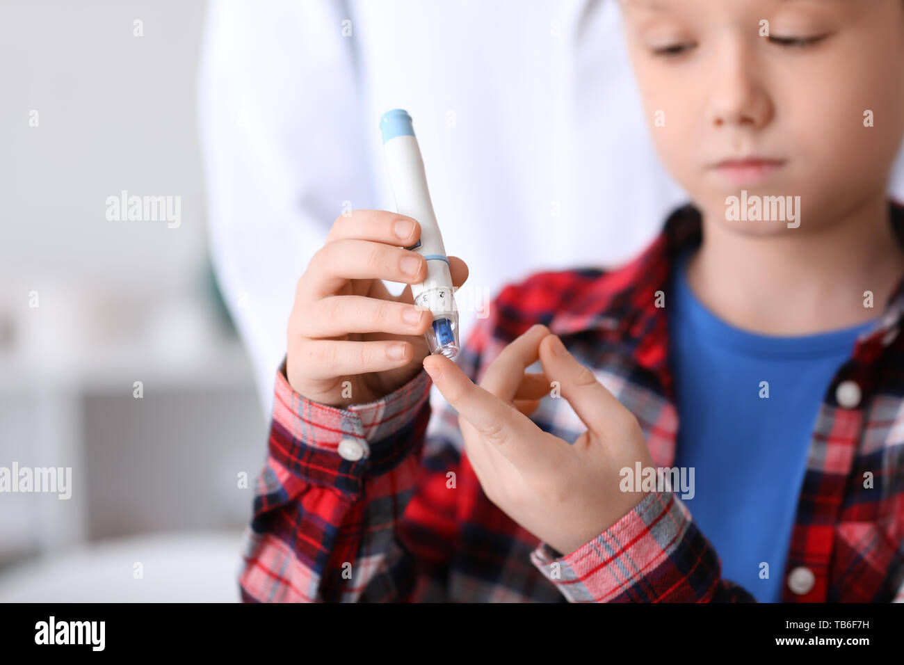 Diabetic child taking blood sample with lancet pen in clinic Stock