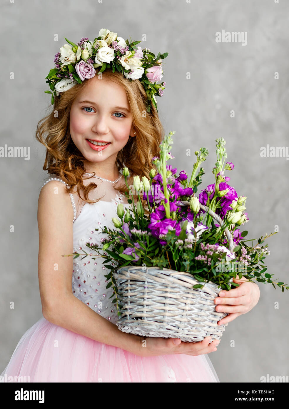 Vertical portrait of a beautiful cute little girl in a wreath of fresh ...