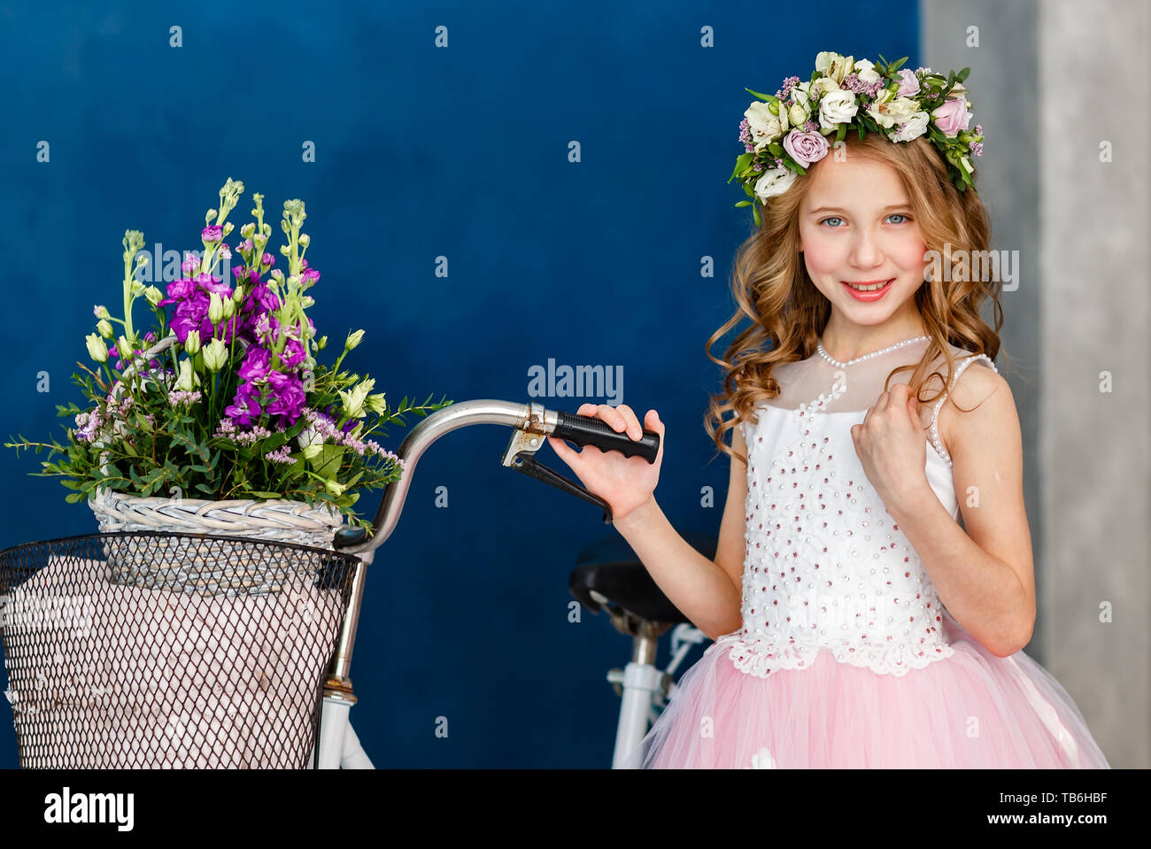 Close-up portrait of a beautiful cute little girl in a wreath of fresh ...