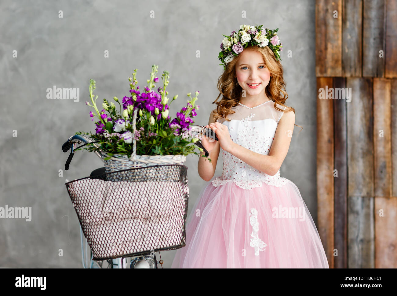 Close-up portrait of a beautiful cute little girl in a wreath of fresh ...