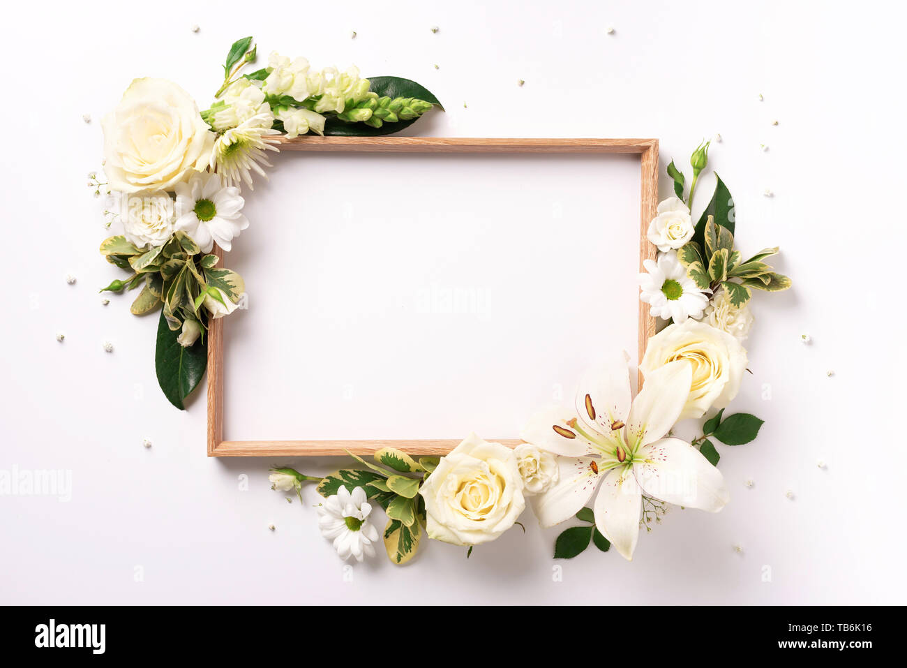 Floral frame of white flowers, green leaves on light paper background ...