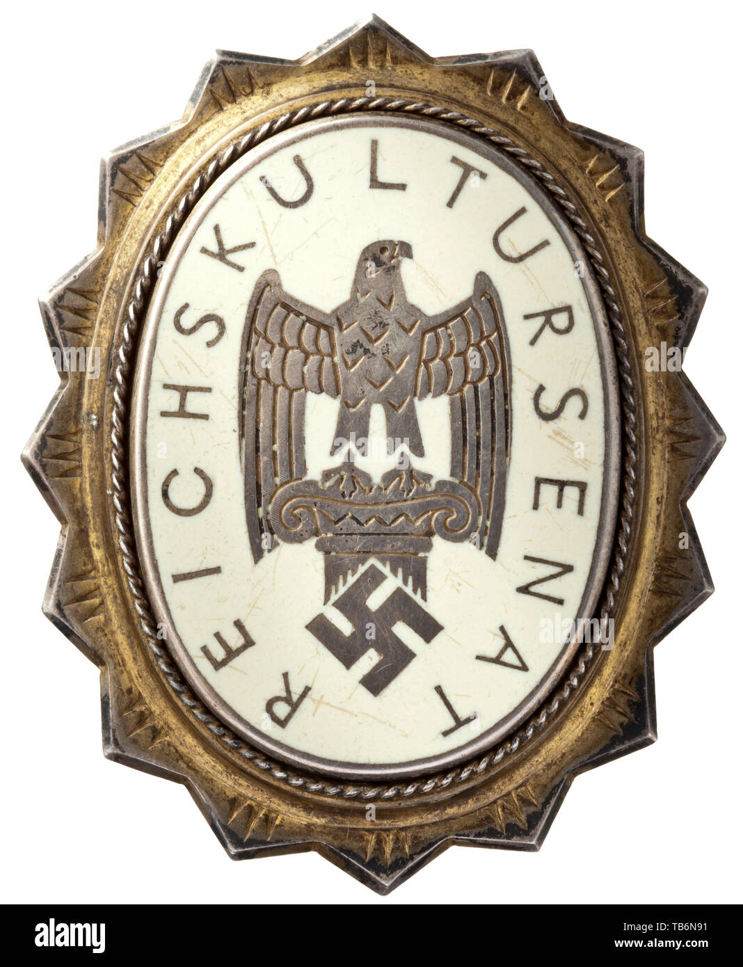 A badge of honour for members of the Reich Senate of Culture - badge with membership number '63', Vertical oval badge with 16-fold serrated border produced in silver, the oval with light ivory-coloured enamel and a depiction of the badge of the Reich Chamber for Culture (an eagle atop an ancient column) with the inscription 'REICHSKULTURSENAT'. The enamelled oval is double-riveted to the base plate, whose reverse bears the struck enrolment number '63' and maker's designation 'DESCHLER MÜNCHEN SILBER 900'. With a thin transverse attachment pin. Small usage-caused scratches. , Editorial-Use-Only Stock Photo