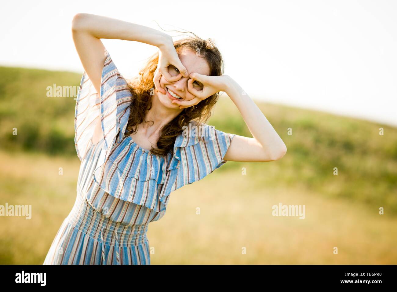 Young pilot girl pretending flying using fake glasses and vintage helmet, on a meadow Stock Photo