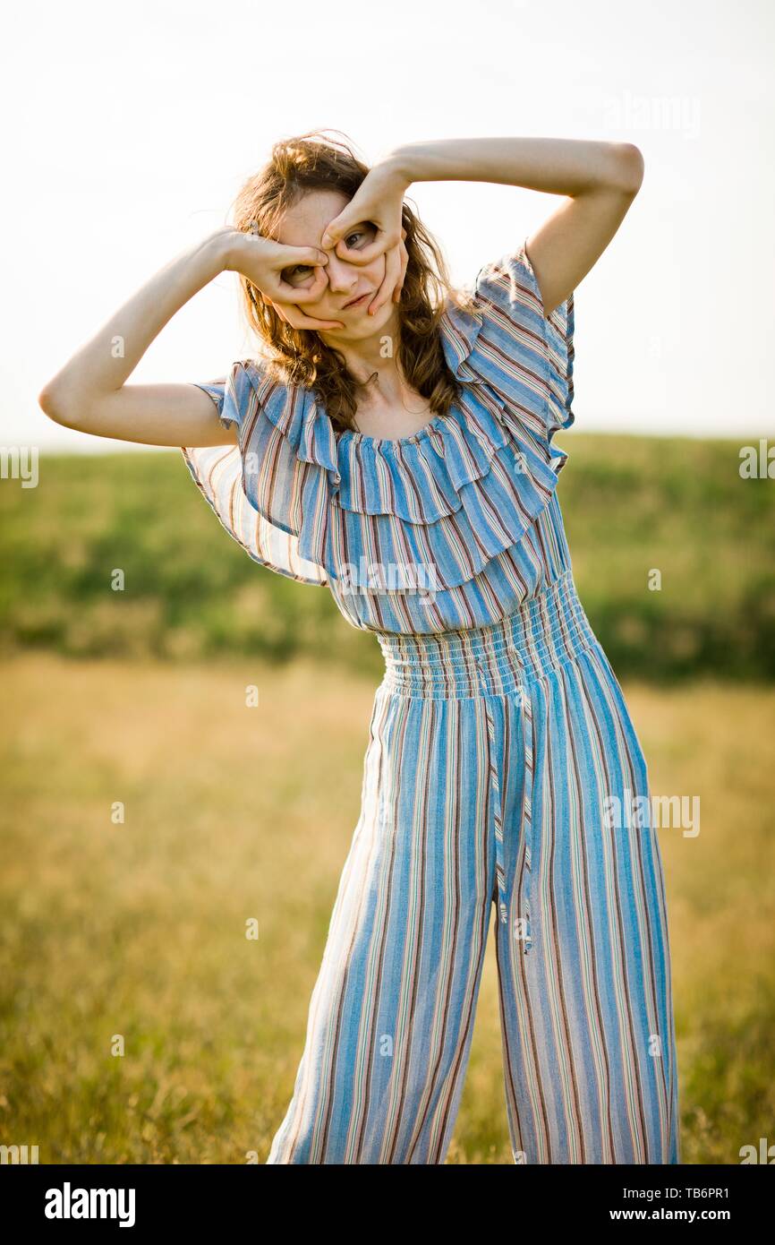 Young pilot girl pretending flying using fake glasses and vintage helmet, outdoor Stock Photo
