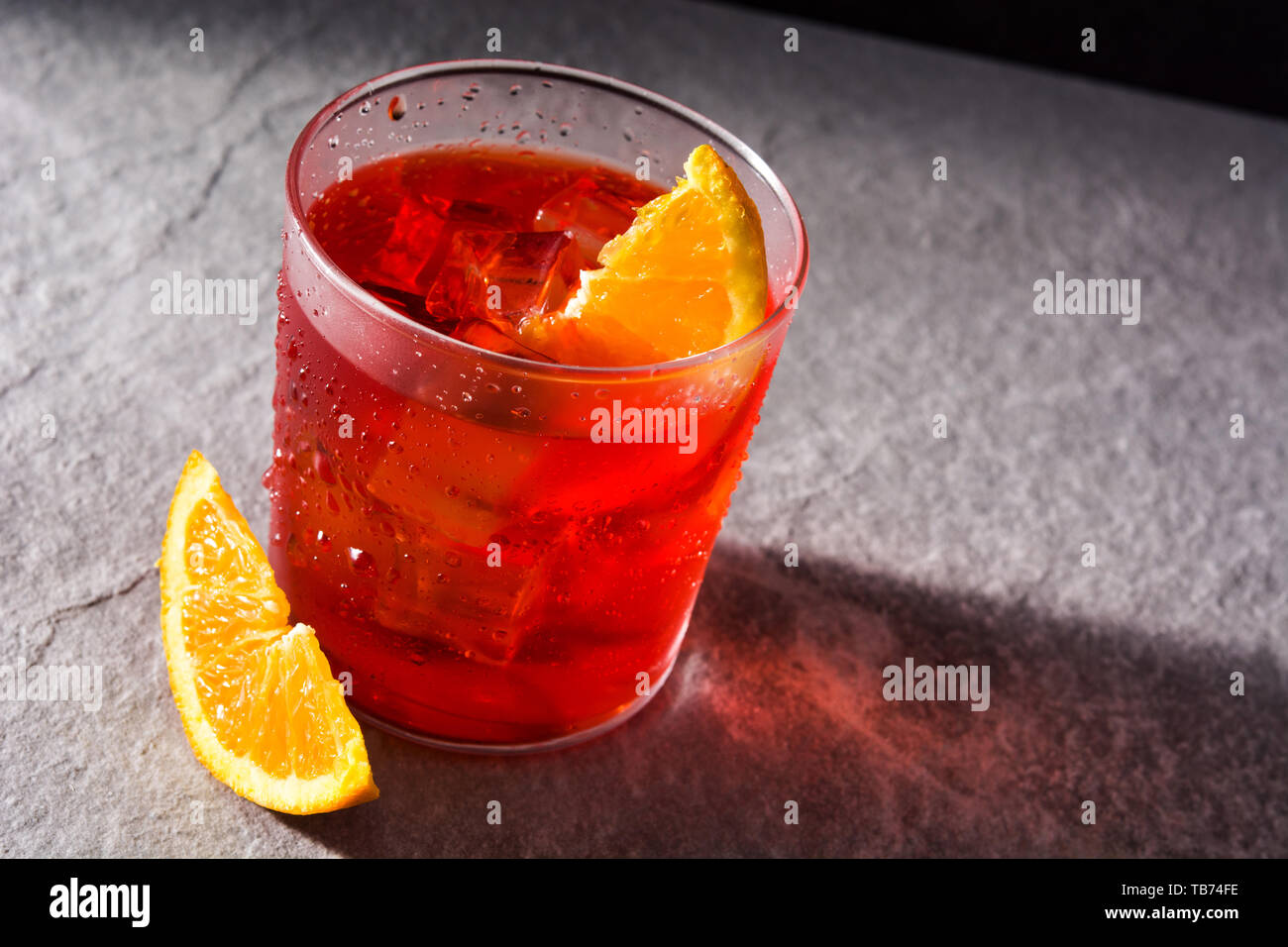 Negroni cocktail with piece of orange in glass on black background Stock Photo