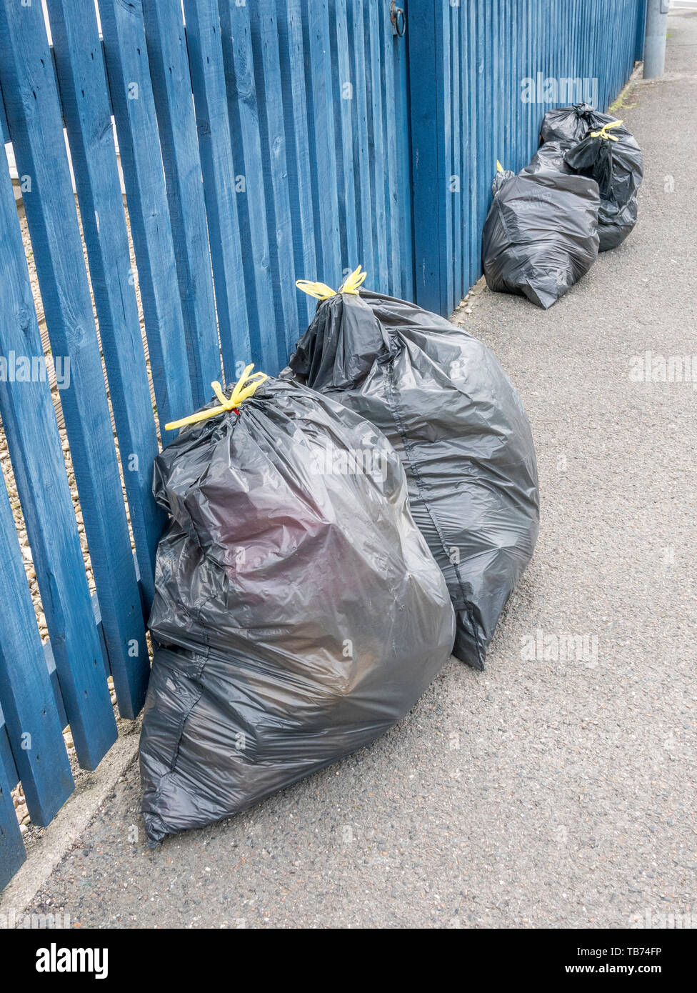 Row of domestic black binliners outside a house. Metaphor garbage, refuse collection, trash